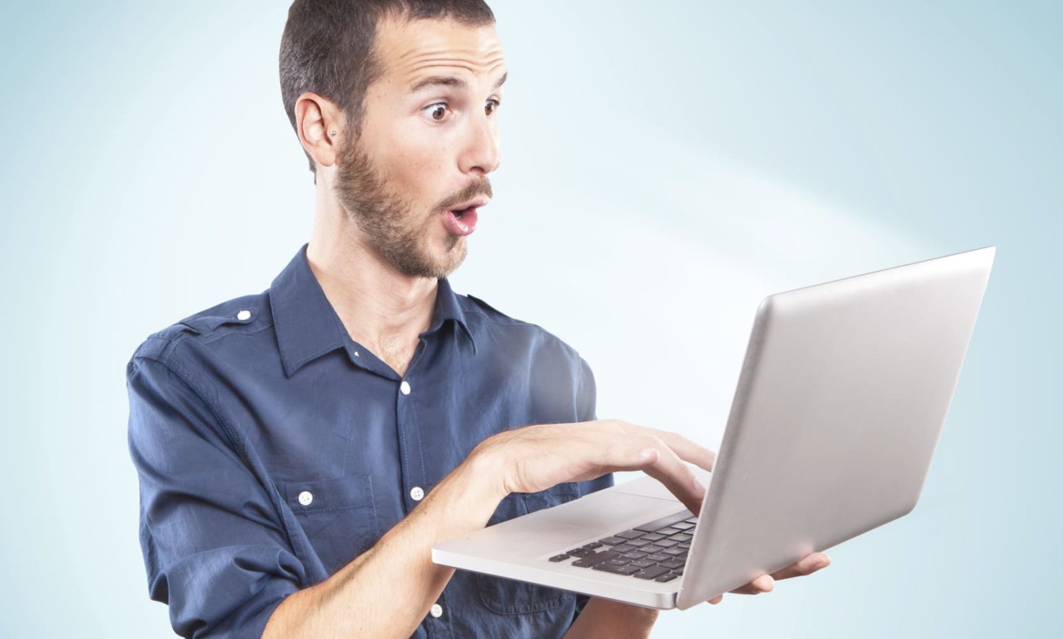 Young man surprised holding a laptop